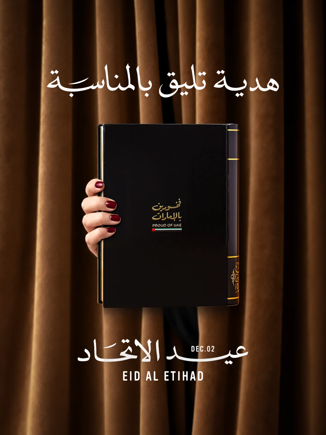 A hand holding the "Proud of UAE" metal book out through a curtain, with the Eid Al Etihad, 2 December lettering